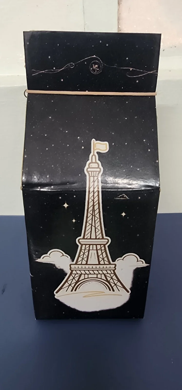 Cara de la caja con ilustración de la Torre Eiffel sobre un fondo nocturno.